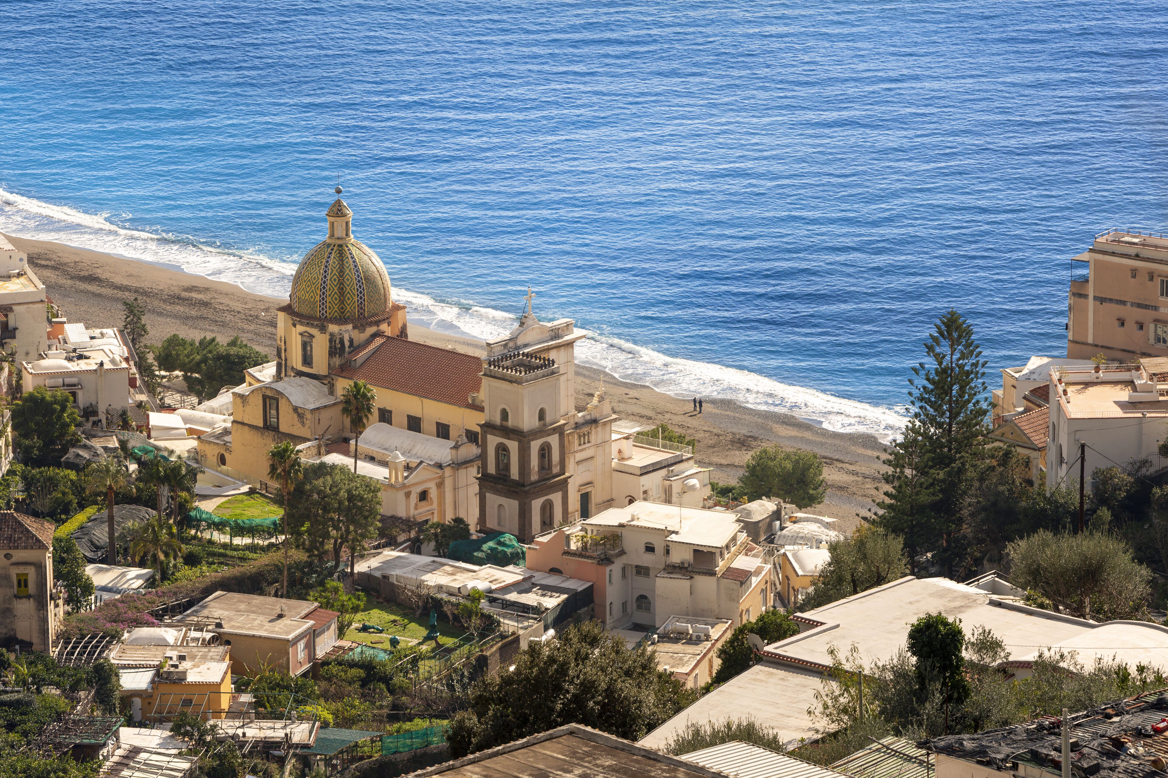 A coastal town with a prominent church featuring a dome, surrounded by residential buildings and a beach.