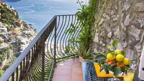 A balcony with a view of a coastal town, a potted plant, and a table with a fruit bowl and drinks. - Relaxing Positano (Positano)