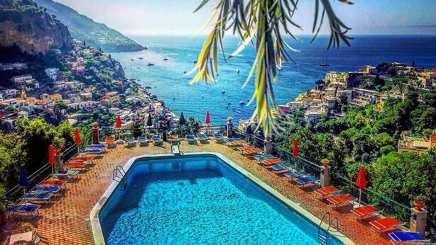 A poolside view overlooking a coastal town with a clear blue sea, surrounded by lush greenery and buildings. - Relaxing Positano (Positano)