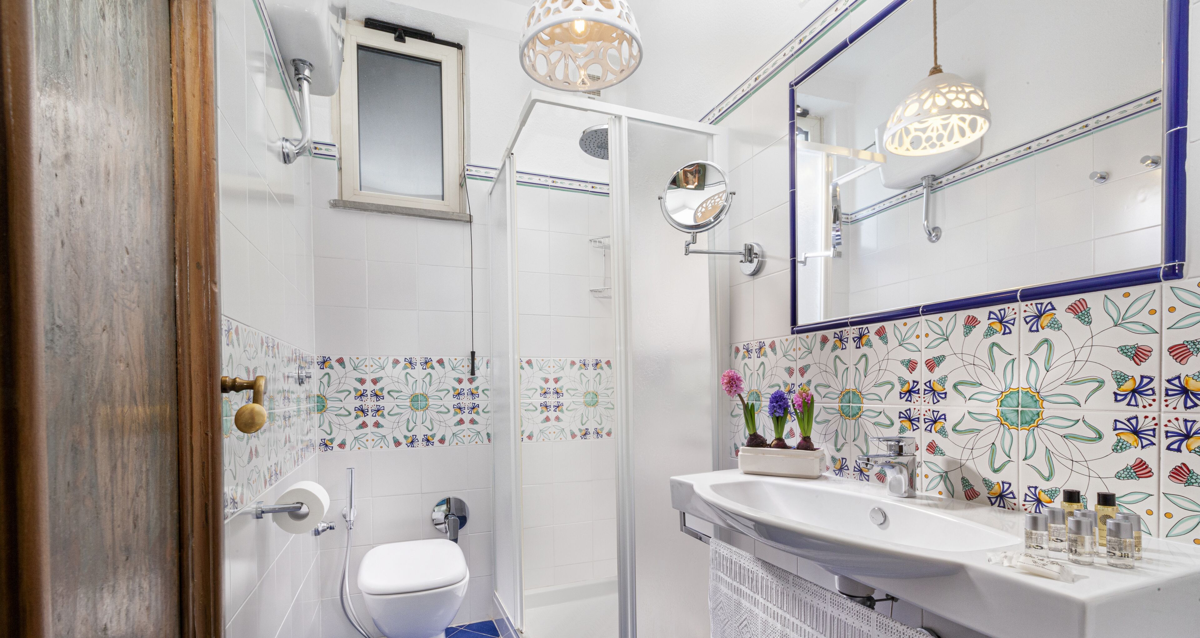 A bathroom with a shower, toilet, sink, and decorative tiles.