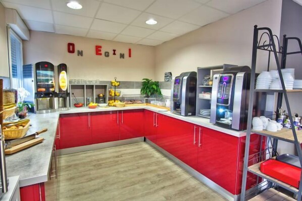 A buffet area with a red counter, beverage dispensers, and a sign that reads 'ONE EGINI'. - Adonis Hotel Bayonne (Mouguerre)