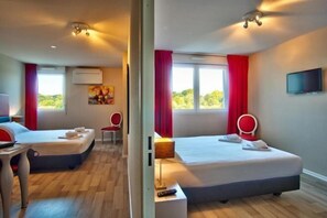 A hotel room with two beds, a desk, a chair, a TV, and a window with curtains. - Adonis Hotel Bayonne (Mouguerre)