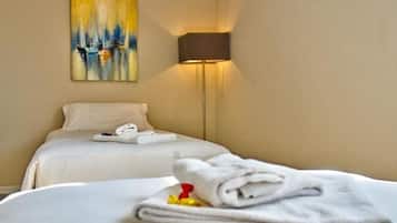 A hotel room with a bed, a painting on the wall, and a lamp.