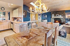 Un vaste espace de vie comprenant un coin salon avec cheminée, une table à manger et une cuisine dotée de meubles en bois.
