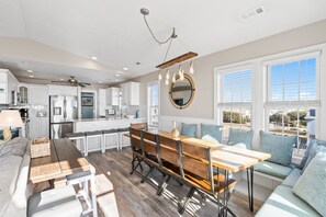 A modern kitchen with white cabinets, a wooden dining table, and a built-in bench seating area.