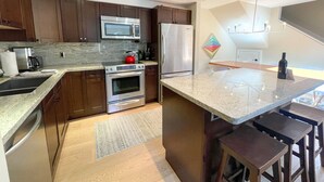 Una cocina moderna con armarios de madera oscura, electrodomésticos de acero inoxidable y encimera de granito.