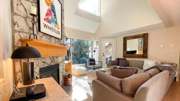 Un salón espacioso con pared de piedra, chimenea, ventana grande y una zona de estar acogedora.