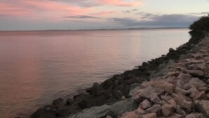 A rocky shoreline with calm water and a sunset sky. - Woody Point Coastal Cottage (Woody Point)