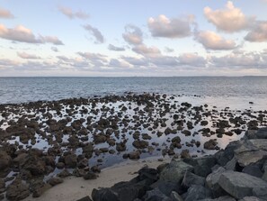 Una línia de costa rocosa amb una mar tranquil·la i un cel amb núvols dispersos.