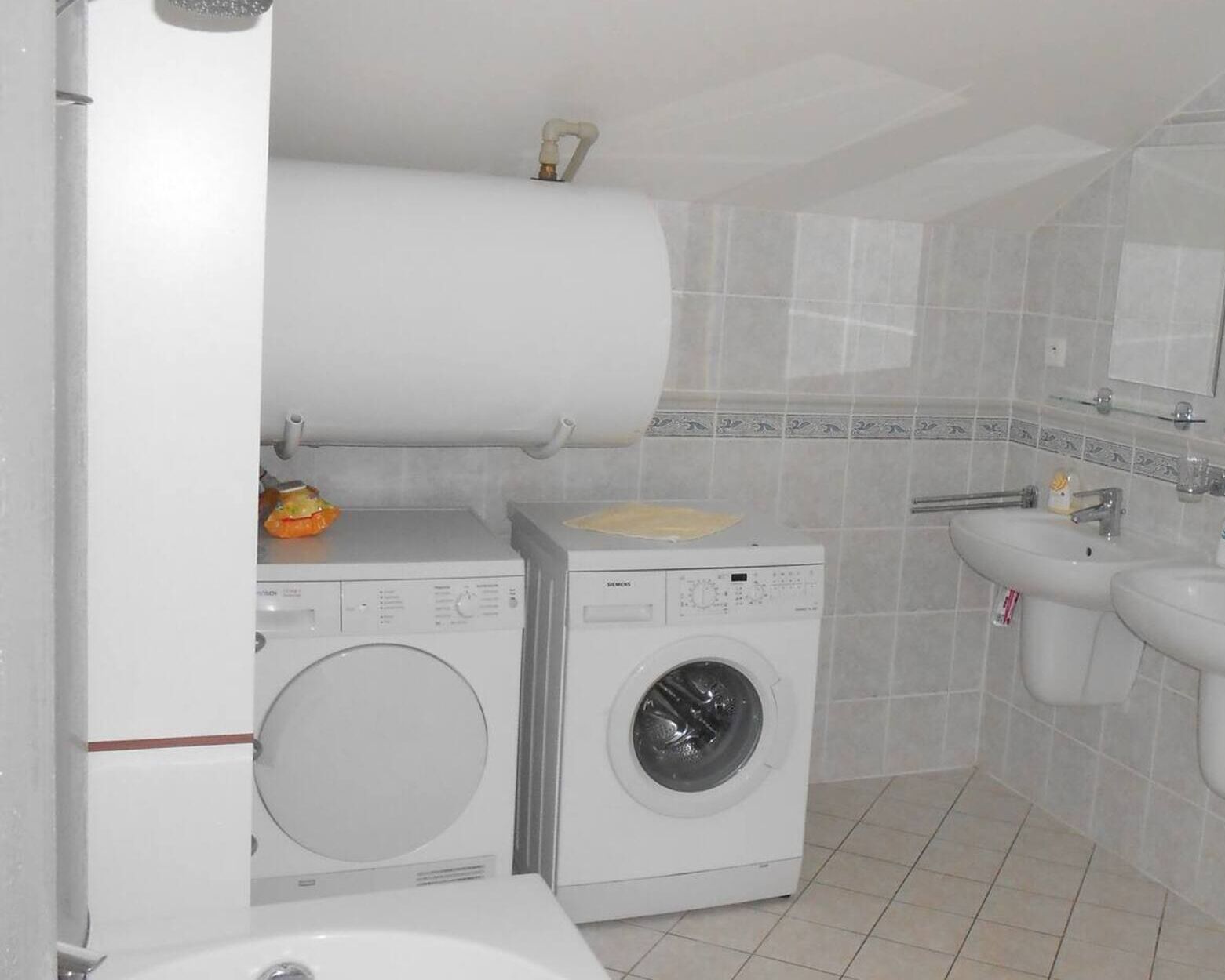 Ein Waschraum mit zwei Waschmaschinen, einem Waschbecken und einer Toilette.