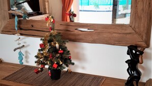 Un banc en bois, un sapin de Noël décoré, un miroir et une sculpture ornementale.
