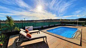 Une piscine avec des chaises longues et une vue sur un paysage lointain.