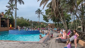 A pool area with a wooden deck, lounge chairs, and palm trees. - San Lameer Villa Rentals 1918 (Southbroom)