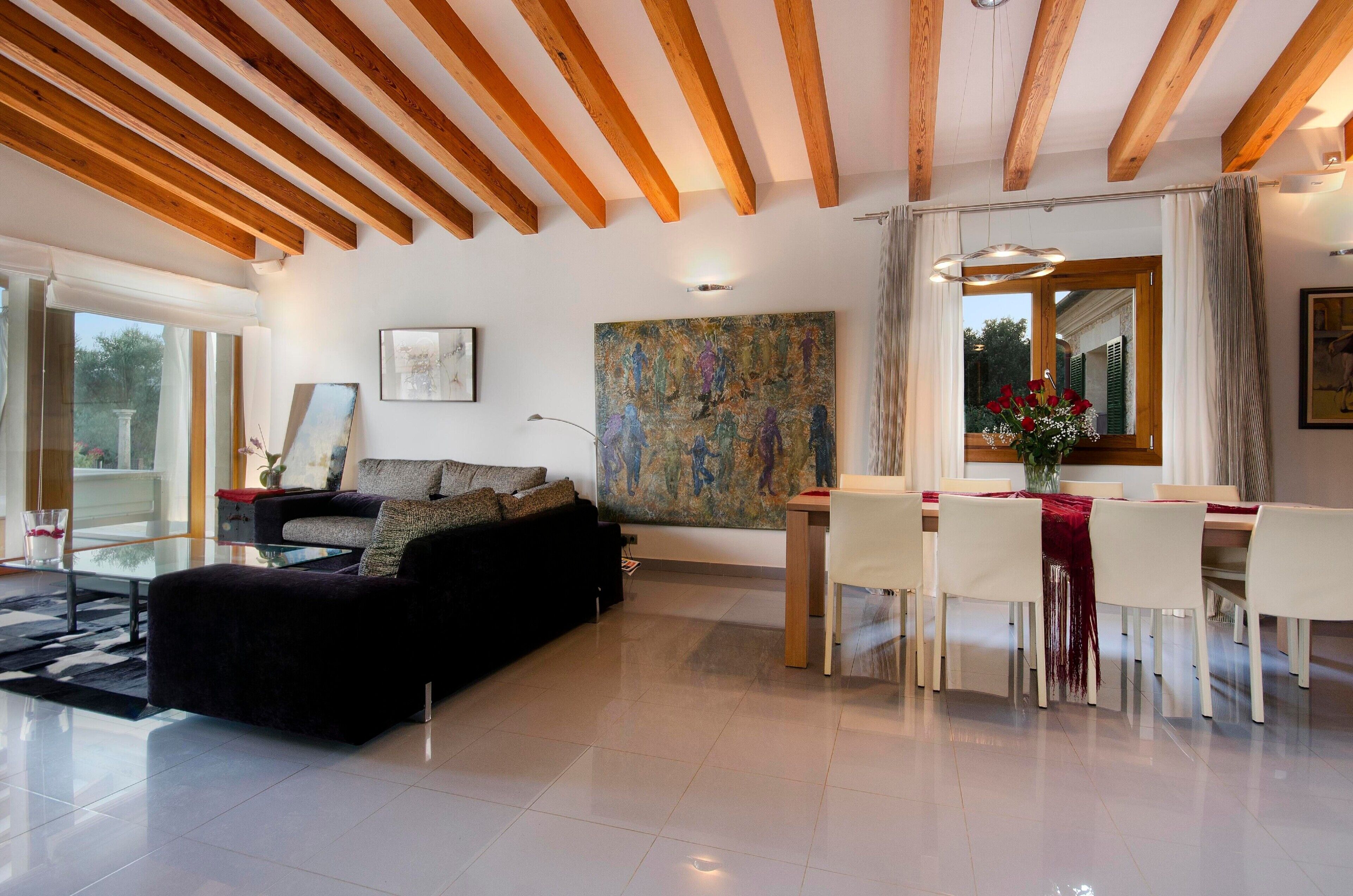 A modern living room with a sofa, dining table, chairs, and artwork on the walls.