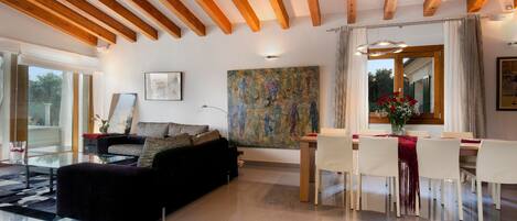 A modern living room with a sofa, dining table, chairs, and artwork on the walls.