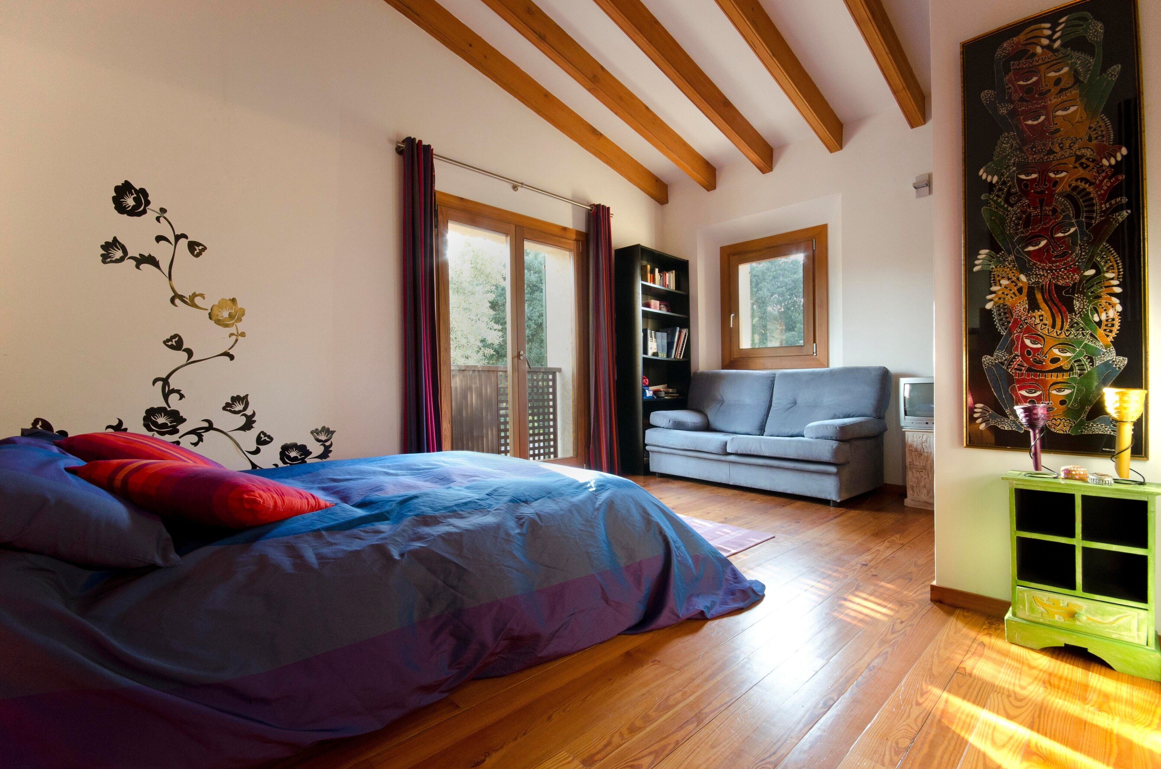 A bedroom with a bed, a bookshelf, a grey sofa, and a green cabinet.