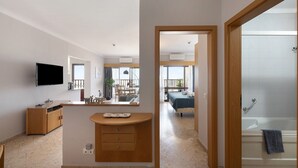 A modern bathroom with a bathtub, a wooden vanity, and a television mounted on the wall. - Apartment 'Sunny Escape' with Sea View, Wi-Fi and Air Conditioning (Portimão)