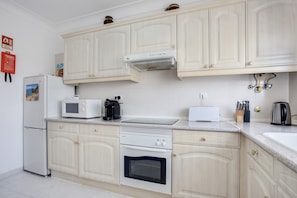 A kitchen with white cabinets, a microwave, a toaster, a coffee maker, and a kettle.