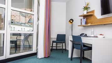 A modern room with a desk, chairs, a radiator, a window with a view of buildings, and a striped curtain.