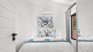 Ein modernes Hotelzimmer mit einem großen Bett, einem Bild an der Wand und einem Fenster mit Vorhängen.