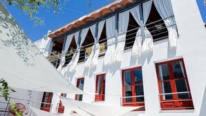 A white building with red-framed windows and white curtains. - EL COLIBRÍ RURAL HOUSE  (Sanlúcar de Guadiana)