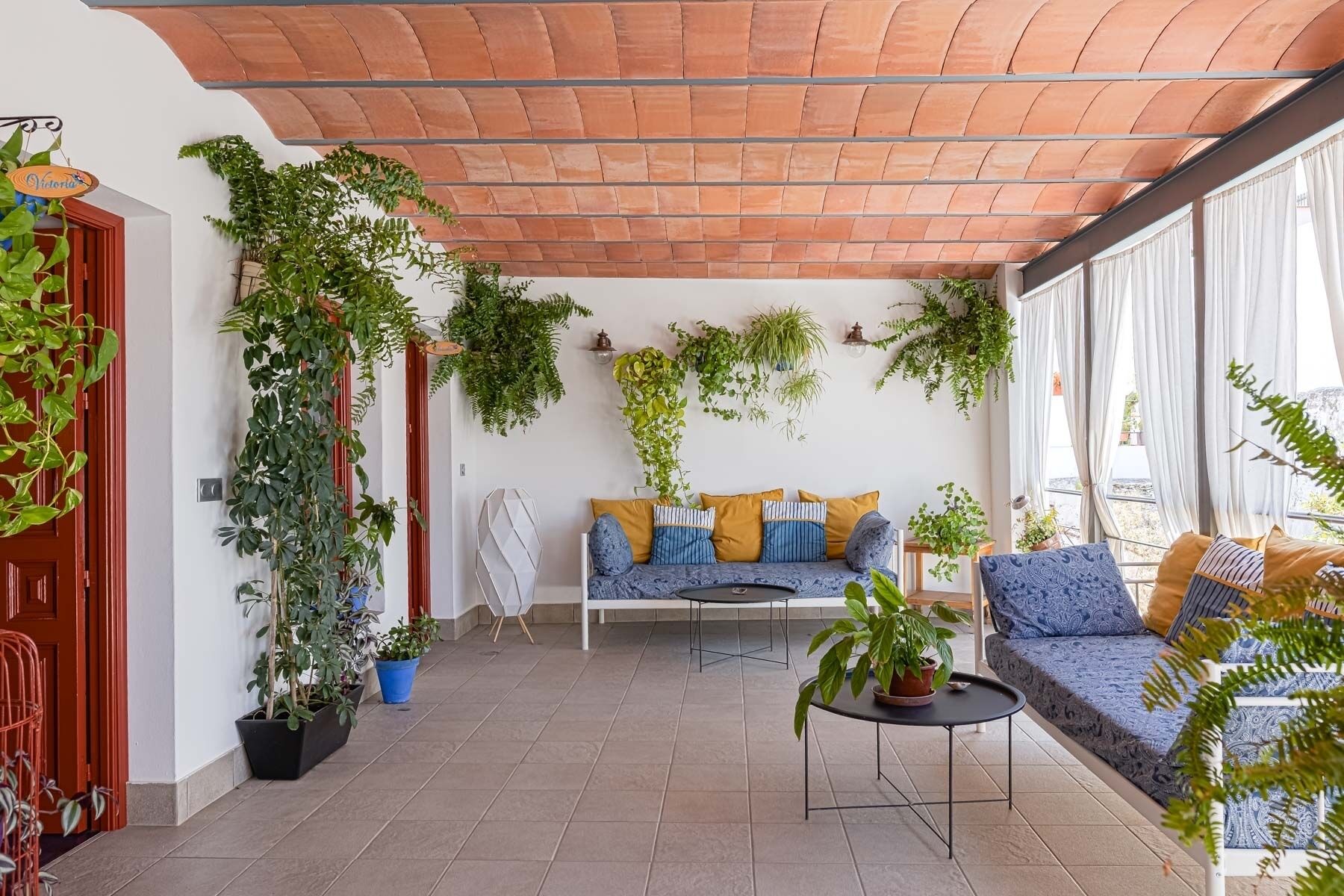 Une terrasse accueillante avec un canapé, une petite table et diverses plantes en pot.