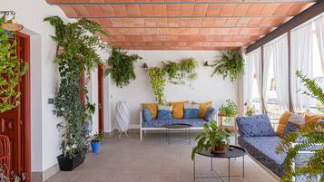 Une terrasse accueillante avec un canapé, une petite table et diverses plantes en pot.
