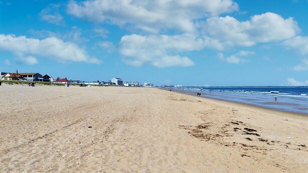 A wide sandy beach with a clear sky and a few buildings in the background. - Beachside Abode 1A (Old Orchard Beach)