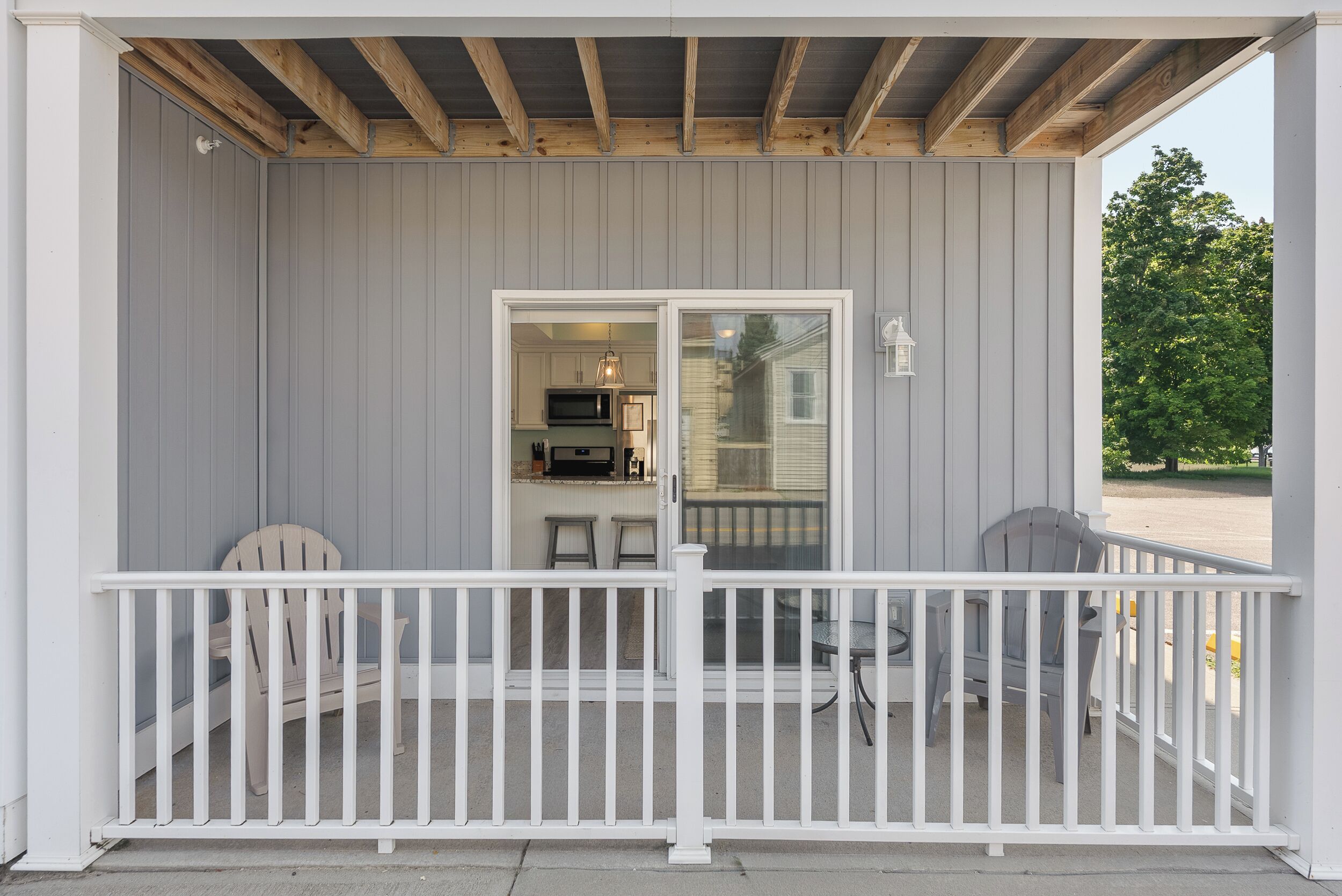 A covered porch with a white railing, a dining table, and two chairs.