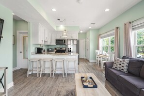A spacious kitchen with a central island, white cabinetry, and a dining area with a table and chairs. - Beachside Abode 2A (Old Orchard Beach)