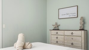 A bedroom with a bed, a dresser, and a wall-mounted sign. - Beachside Abode 2A (Old Orchard Beach)