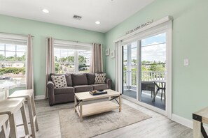 A living room with a sofa, coffee table, and a view of the outdoors through a sliding glass door.