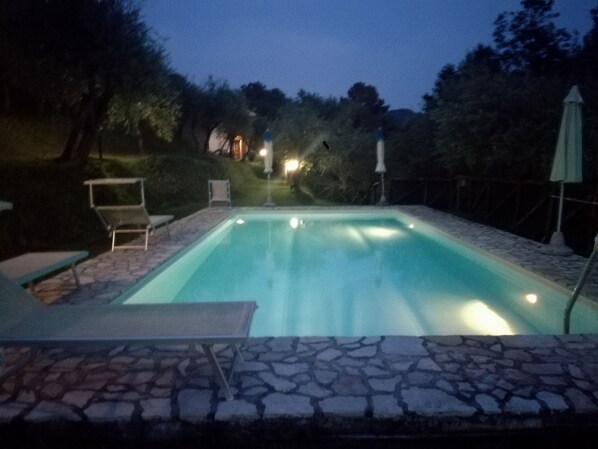 A rectangular swimming pool with a stone border, surrounded by a patio with chairs and a table. - A little, intimate paradise! (Camaiore)
