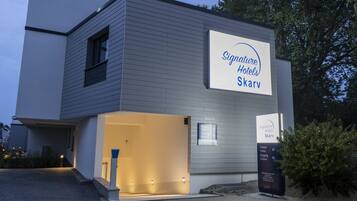 A modern hotel building with a sign for Signature Hotels Skarv.