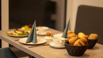 A breakfast setting with croissants, bread, and a cup of coffee on a table.