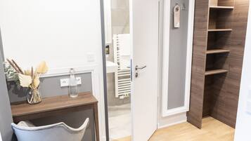 Un baño con tocador de madera, un perchero y una zona de ducha.
