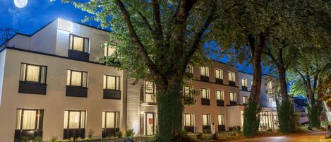 A modern hotel with multiple floors, large windows, and a well-maintained garden area.