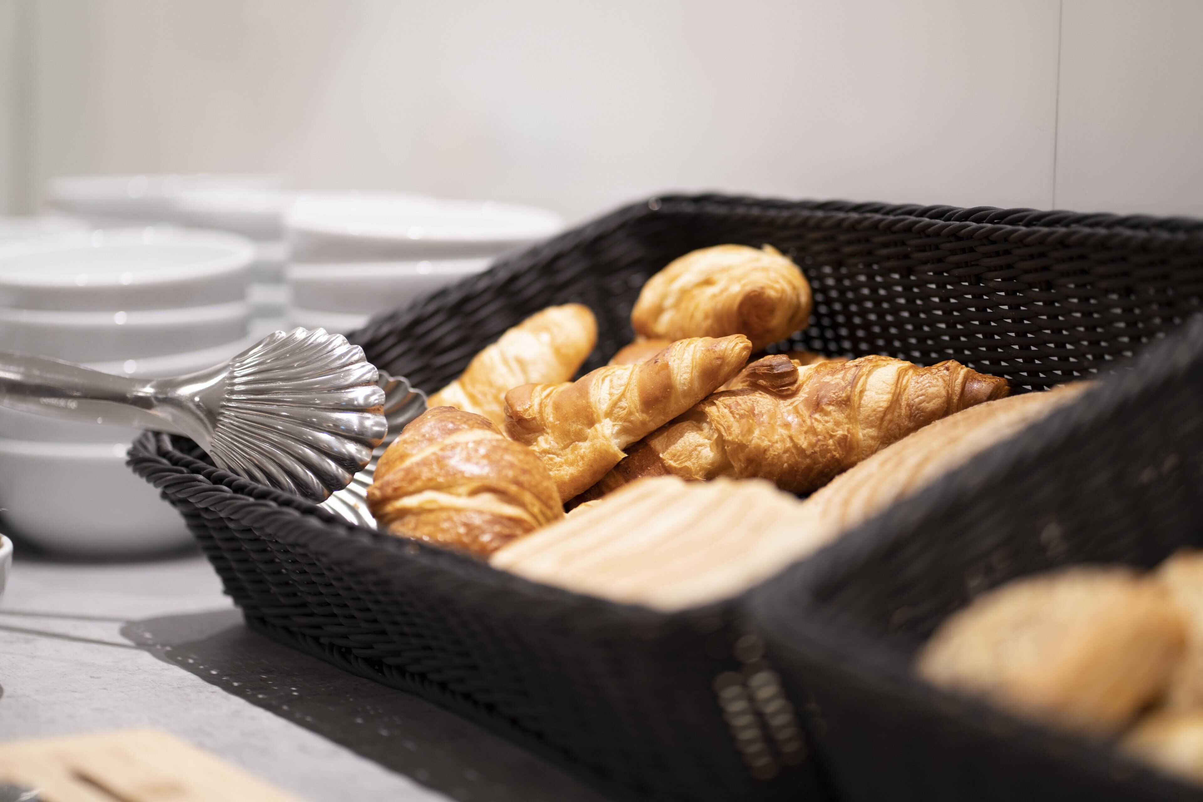 Una cesta de cruasanes y un tenedor sobre una mesa.