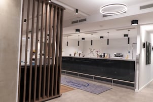 A modern reception area with a black reception desk, pendant lighting, and a decorative rug.