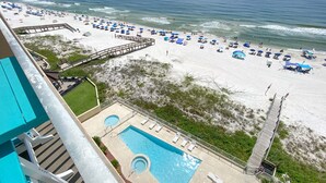 A beach resort with a swimming pool, beach umbrellas, and a wooden walkway.
