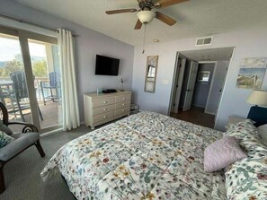 Une chambre à coucher comprenant un lit, une commode, un téléviseur et un ventilateur de plafond.
