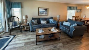 A living room with a sofa set, a coffee table, and a dining area with chairs.