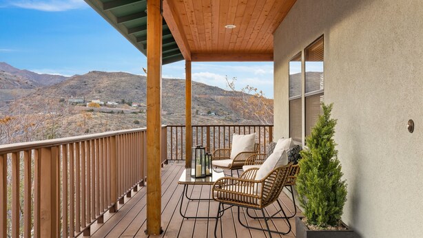 A wooden deck with wicker chairs and a table, overlooking a mountainous landscape. - Large Private Home in Jerome, AZ w/ Full Kitchen (Jerome)