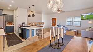 A modern kitchen with a central island, a dining area with a wooden table, and a living room with a sofa and TV. - Large Private Home in Jerome, AZ w/ Full Kitchen (Jerome)