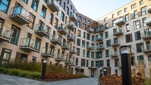 Un edificio residencial de varios pisos con balcones, un patio empedrado y un sendero.
