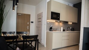 Una cocina moderna con horno integrado, cafetera y lavaplatos. Cuenta con un comedor con mesa y sillas.