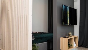 Una sala moderna con una cama, un televisor montado en la pared y un panel de madera.
