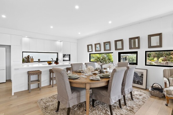 Una cocina moderna con armarios blancos, una isla central y un comedor con una mesa redonda y sillas.