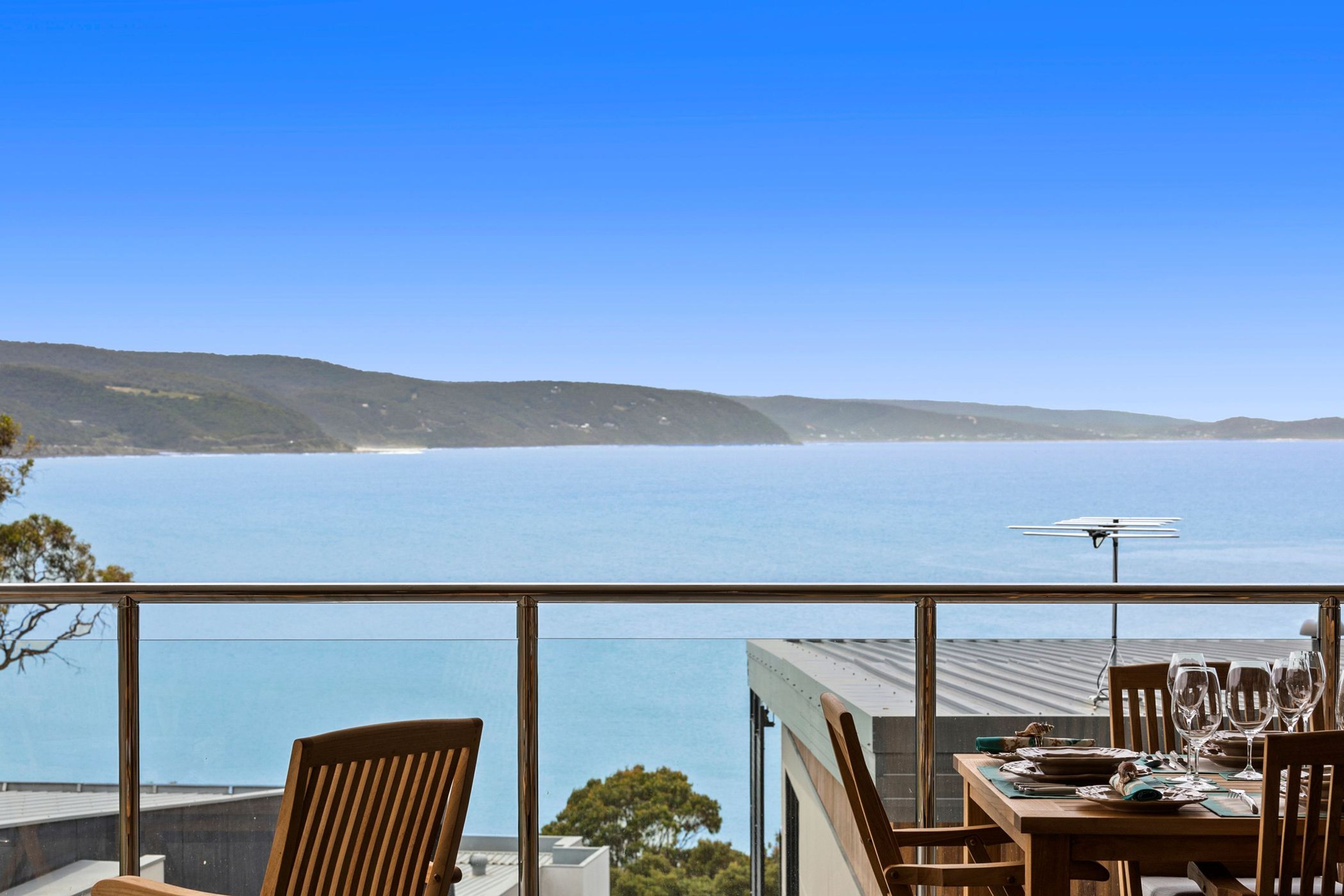 A dining area with a table set for two, overlooking a coastal view.