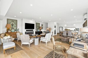 Amplia sala de estar con chimenea, varios espacios de descanso y un comedor con una mesa grande.